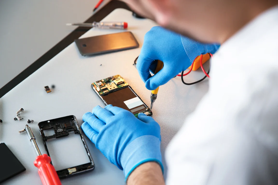 Technician Repairing Mobile Phone at Table, Closeup